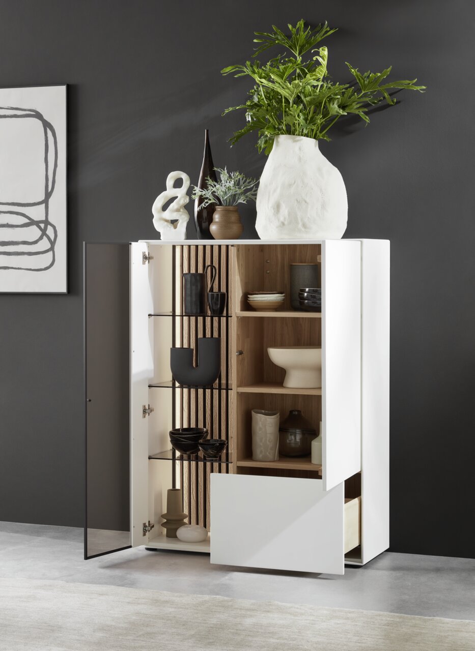 Modernes Highboard LUCIANO von Johann Jakob mit Glas links, offene Perspektive, dekoriert mit Vasen und Pflanzen, zeigt Innenregale mit Geschirr.