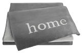 Graue Wohndecke mit dem Wort 'home' in weißer Schrift, aus einer leicht seitlichen Perspektive fotografiert.