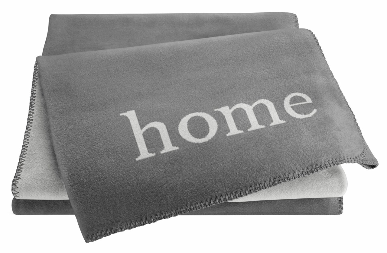 Graue Wohndecke mit dem Wort 'home' in weißer Schrift, aus einer leicht seitlichen Perspektive fotografiert.