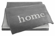Graue Wohndecke mit dem Wort 'home' in weißer Schrift, aus einer leicht seitlichen Perspektive fotografiert.