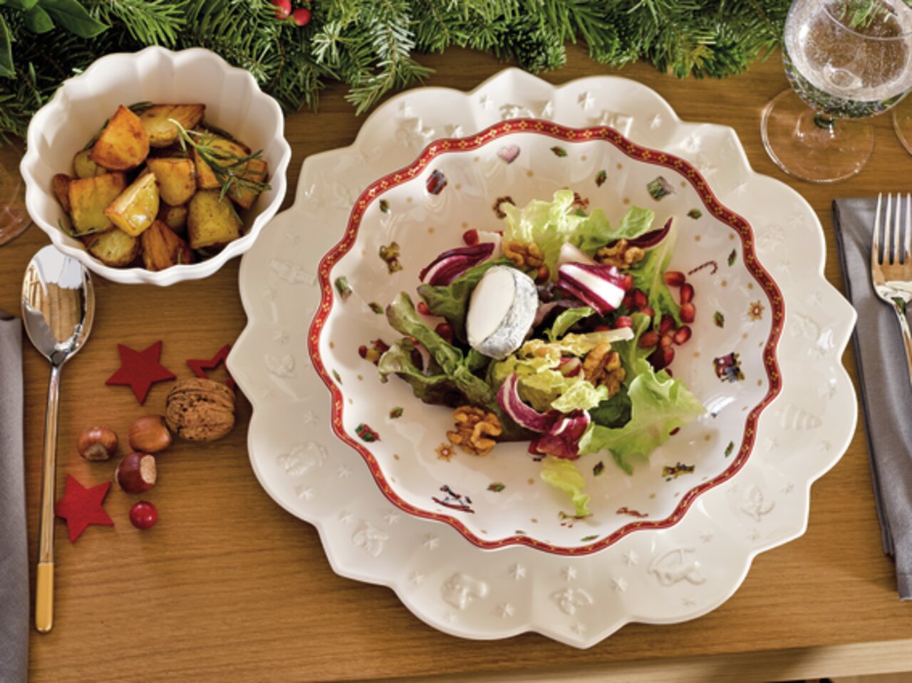 Große, dekorative Schale mit weihnachtlichem Muster, gefüllt mit Salat, aus der Vogelperspektive auf einem festlich gedeckten Tisch.