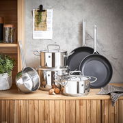 Topfset Twin Classic 6-tlg. aus Edelstahl, bestehend aus mehreren Töpfen und Pfannen, auf einer Holzoberfläche vor einer grauen Wand präsentiert. Perspektive: Frontalansicht.