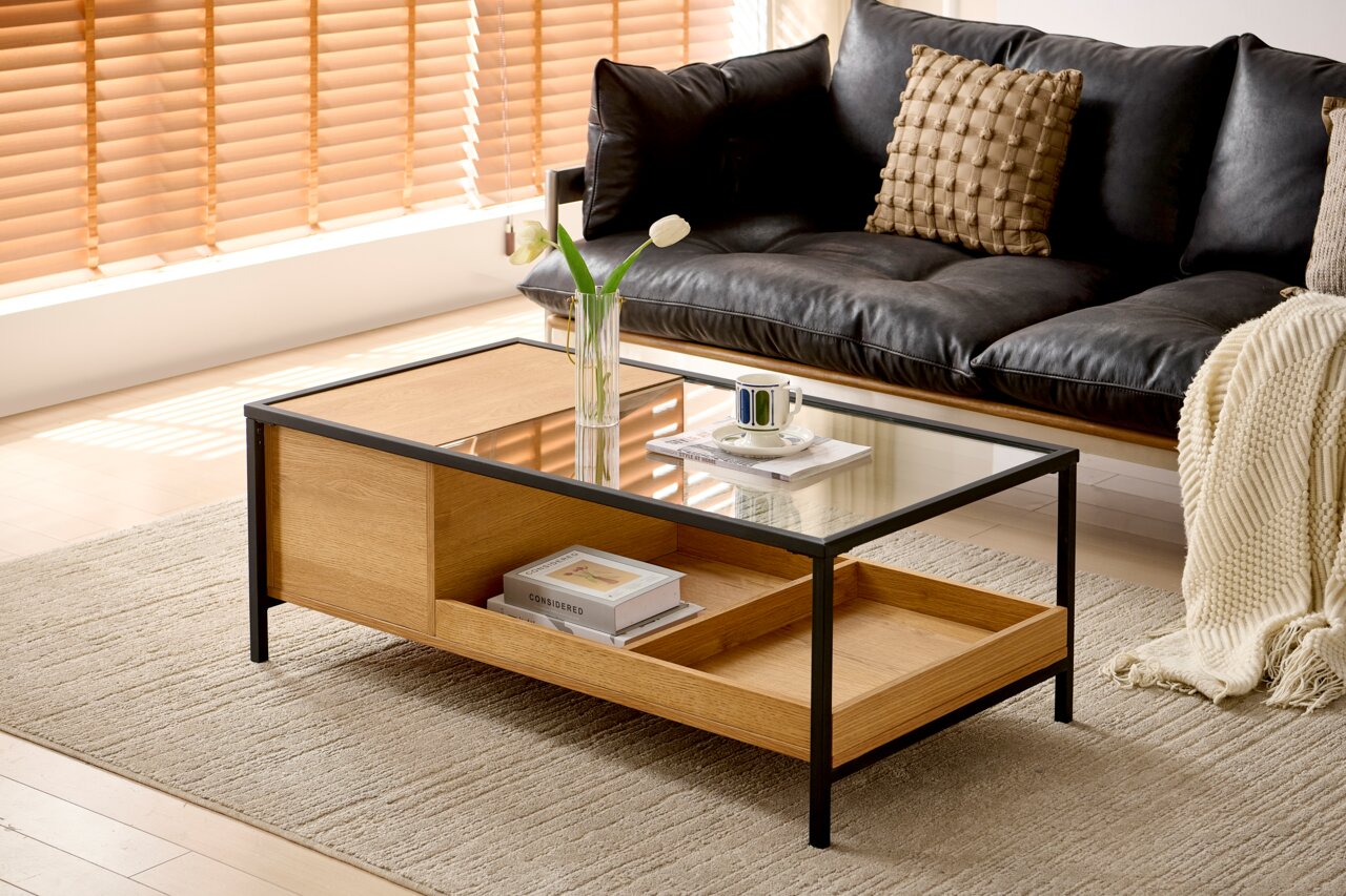 Novel Salontafel LUNA Moderne salontafel van hout en glas met een zwart metalen frame, gezien vanaf de zijkant, versierd met een vaas en een kopje op een tapijt voor een bank.
