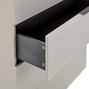Geöffnete Schublade eines modernen weißen Schranks mit schwarzer Innenverkleidung, Detailaufnahme in schräger Seitenansicht