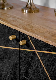 Nahaufnahme einer Kommode mit schwarzer Steinoptik und goldenen Griffen, von oben betrachtet.