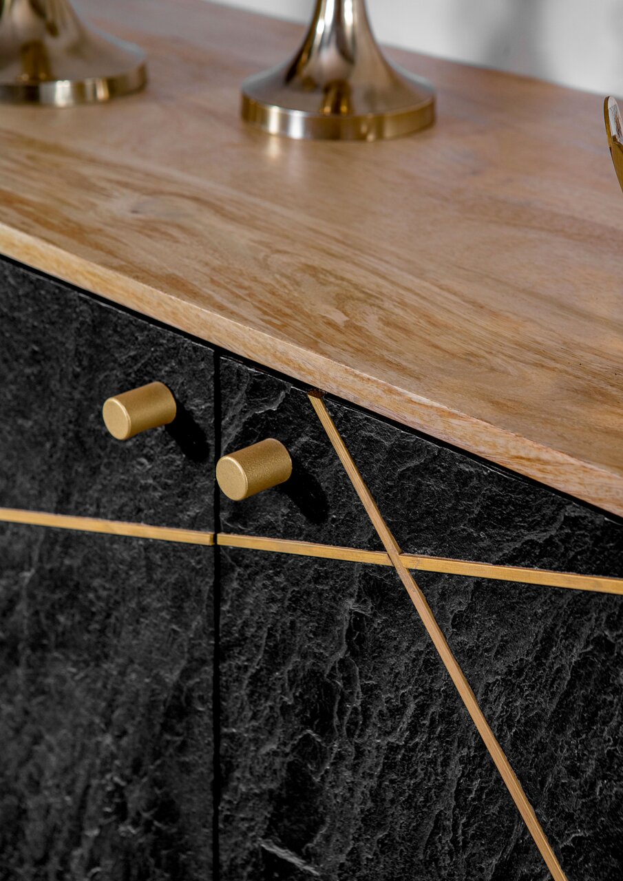 Nahaufnahme einer Kommode mit schwarzer Steinoptik und goldenen Griffen, von oben betrachtet.