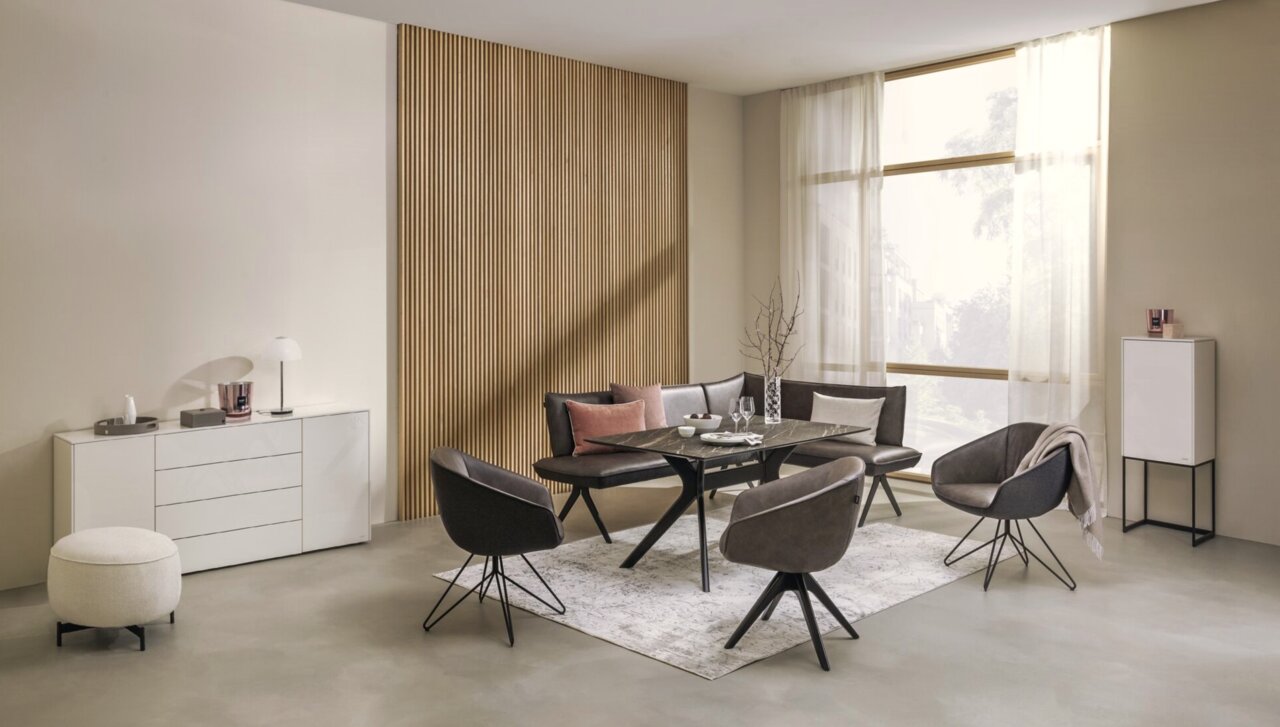 Moderne Eckbank in einem stilvollen Wohnzimmer, umgeben von eleganten Stühlen und einem Tisch, mit Blick auf eine große Fensterfront.