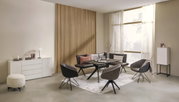 Een moderne hoekbank in een stijlvolle woonkamer, omringd door elegante stoelen en een tafel, met uitzicht op een grote raampartij.