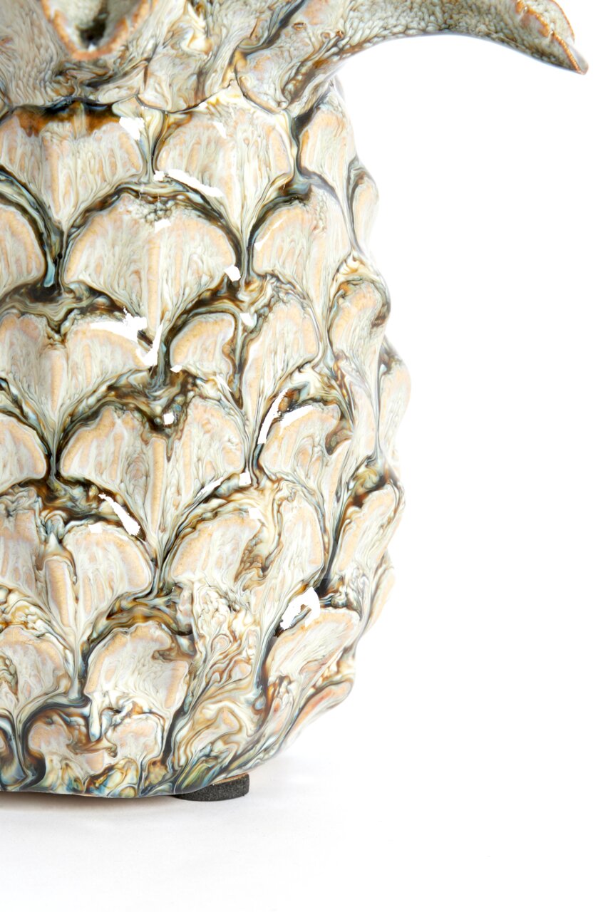 Nahaufnahme eines kunstvoll verzierten Ornaments mit detailliertem, blattähnlichem Muster in natürlichen Farbtönen, seitliche Perspektive.