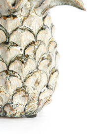 Nahaufnahme eines kunstvoll verzierten Ornaments mit detailliertem, blattähnlichem Muster in natürlichen Farbtönen, seitliche Perspektive.