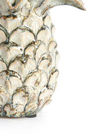 Nahaufnahme eines kunstvoll verzierten Ornaments mit detailliertem, blattähnlichem Muster in natürlichen Farbtönen, seitliche Perspektive.