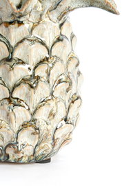 Nahaufnahme eines kunstvoll verzierten Ornaments mit detailliertem, blattähnlichem Muster in natürlichen Farbtönen, seitliche Perspektive.