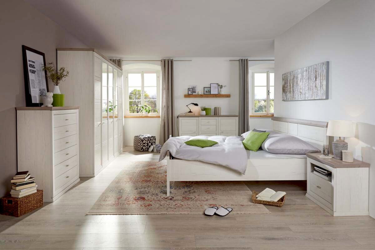 Helle und moderne Schlafzimmeransicht mit einer Nachtkommode neben einem Bett, dekoriert mit grünen Kissen und einem Teppich auf Holzboden.