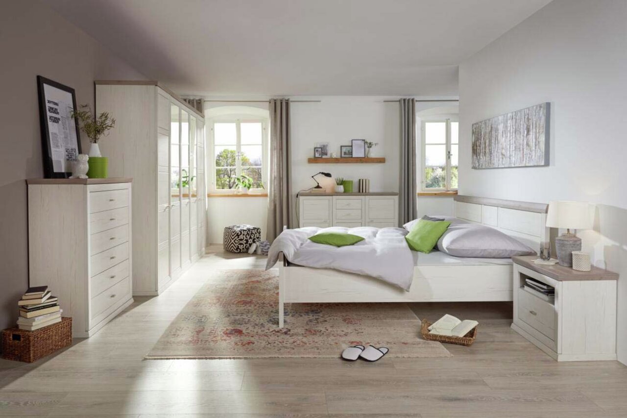 Helle und moderne Schlafzimmeransicht mit einer Nachtkommode neben einem Bett, dekoriert mit grünen Kissen und einem Teppich auf Holzboden.
