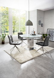 Moderner Essbereich mit rundem Glastisch und vier grauen Stühlen auf einem weißen Teppich, seitliche Perspektive.