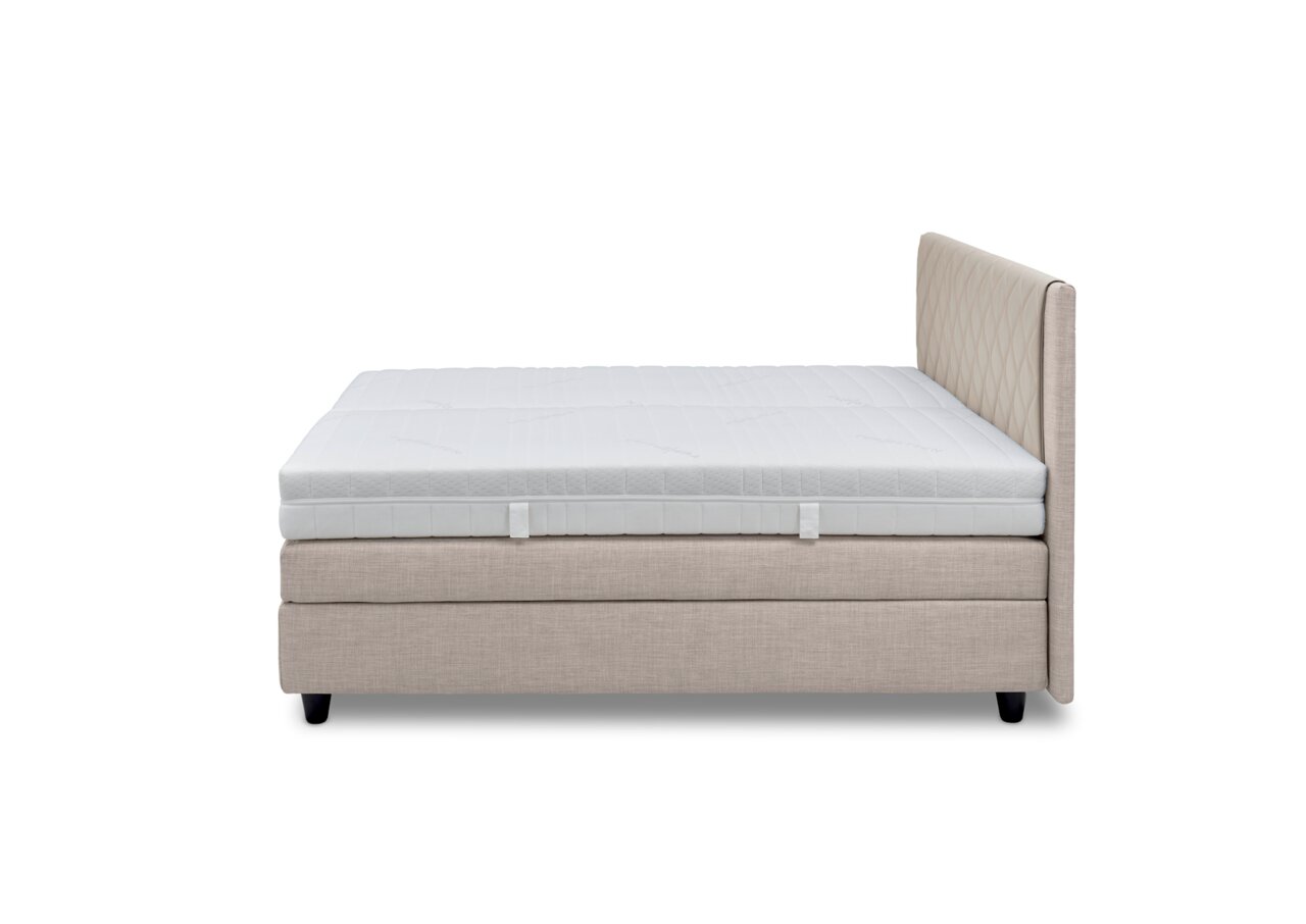 Zijaanzicht van een boxspringbed met een beige stoffen bekleding en een wit matras.
