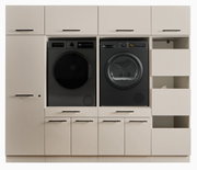 Frontansicht einer modernen Waschküchen-Schrankwand in Beige mit schwarzen Griffen, integrierter schwarzer Waschmaschine und schwarzem Wäschetrockner sowie offenen Ablagefächern rechts.