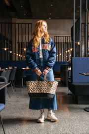 Frau in einem modernen Café hält eine Einkaufstasche mit Leopardenmuster in der Hand, Vorderansicht