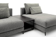 Moderner Anstelltisch in dunklem Holz zwischen zwei grauen Sofas, seitliche Perspektive.