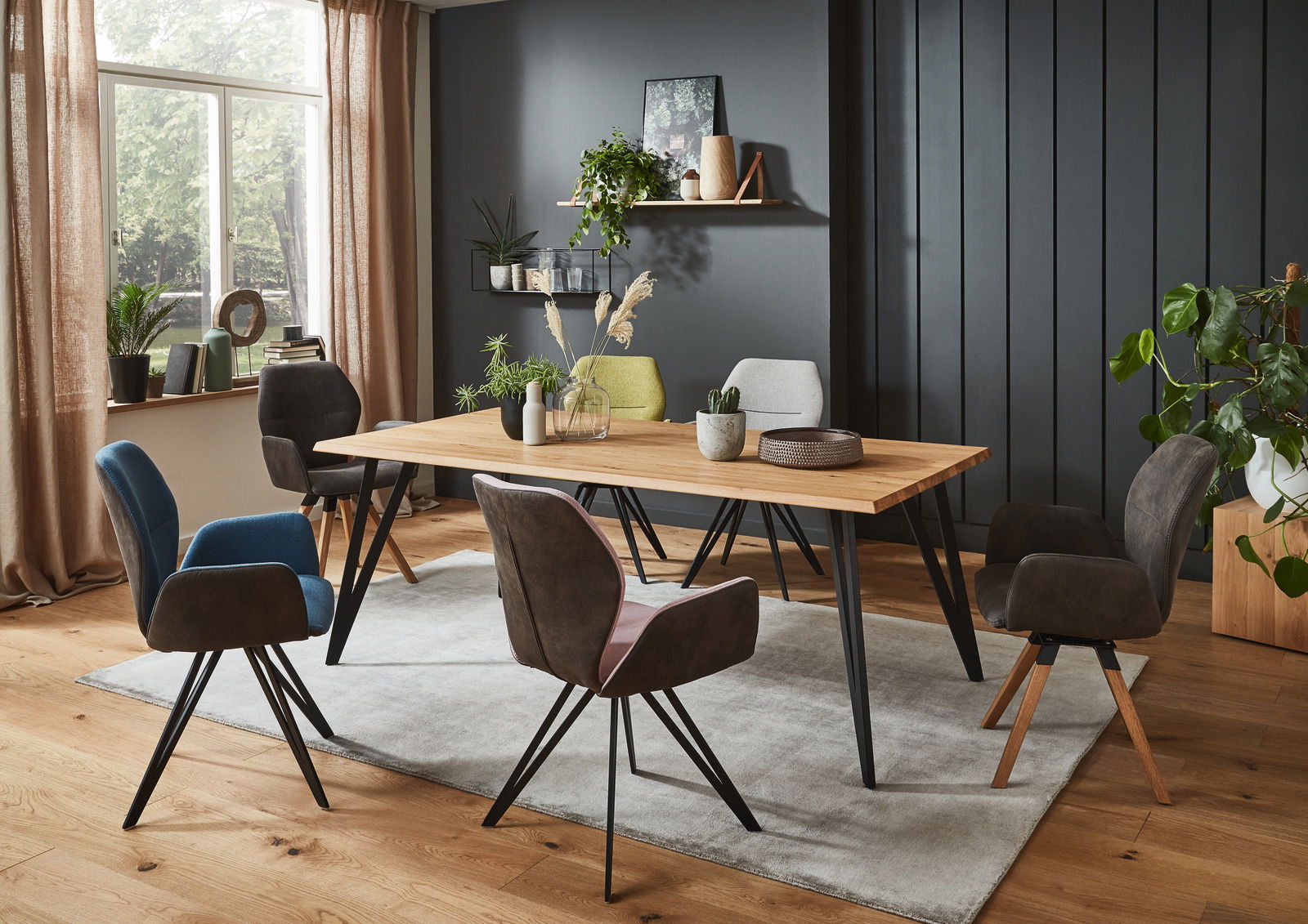 Valnatura Armlehnenstuhl PIANO Esszimmer mit modernem Esstisch aus Holz und sechs Armlehnenstühlen in verschiedenen Farben, seitliche Perspektive.