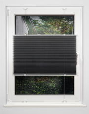 Schwarzes Plissee am Fenster, halb heruntergelassen, mit Blick auf einen Garten im Hintergrund.