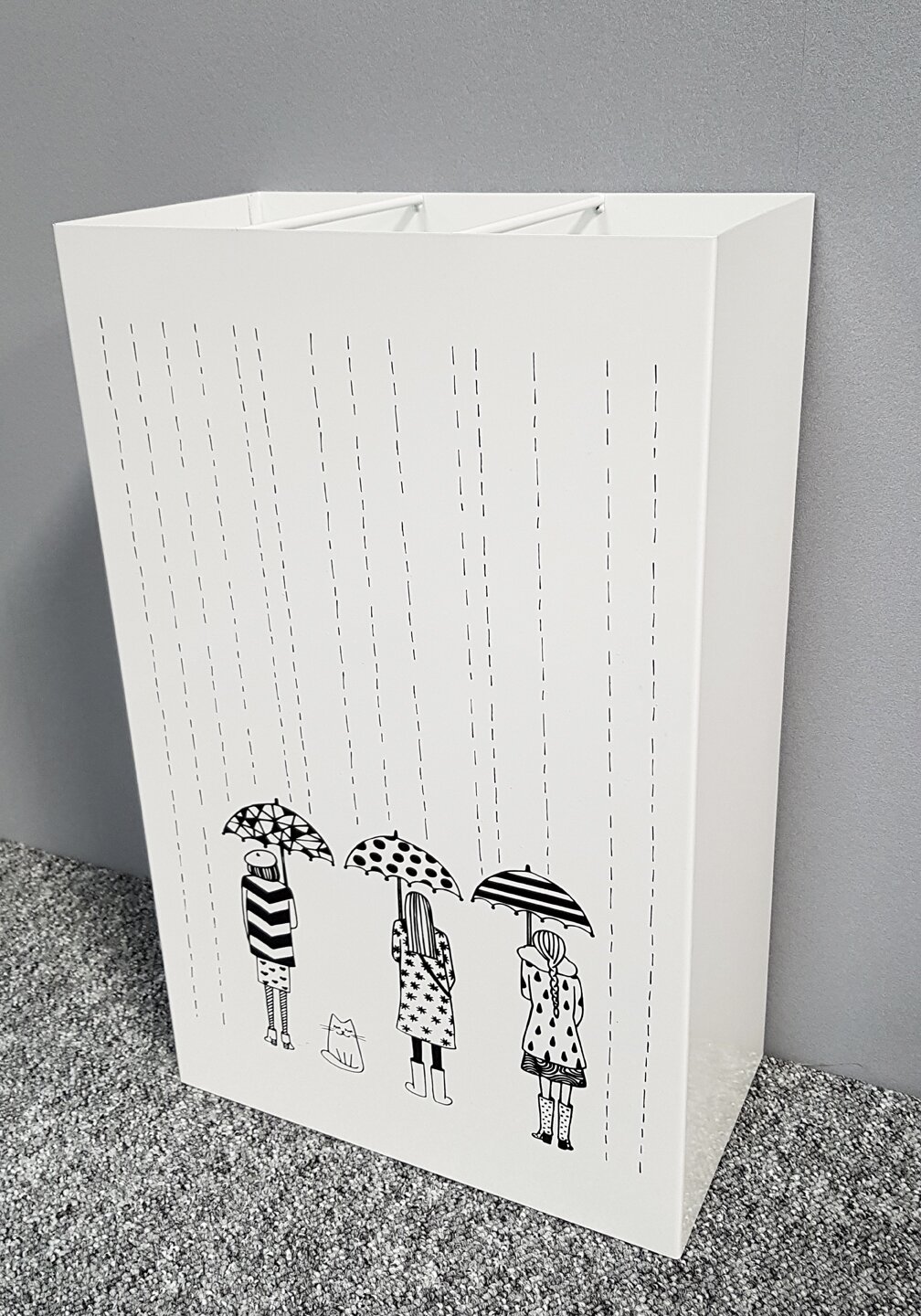 Weißer Papierkorb/Aufbewahrungsbehälter mit schwarz-weißer Regenschirm-Illustration und Regenlinien, schräg von vorne links fotografiert