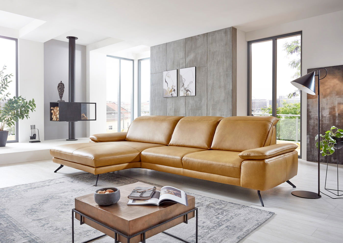 Moderne Longchairkombination in senffarbenem Leder, seitliche Perspektive in einem hellen Wohnzimmer mit großen Fenstern und stilvoller Dekoration.