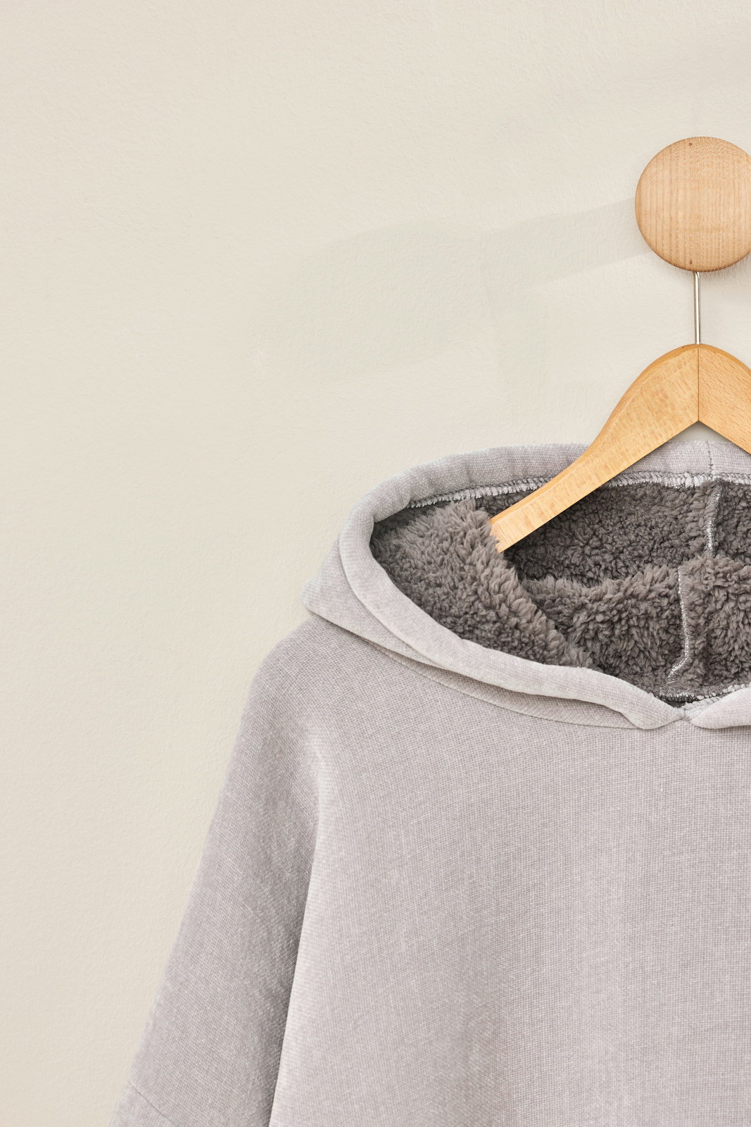 Grauer Lounge-Hoodie mit weichem Innenfutter, auf einem Kleiderbügel von vorne fotografiert.