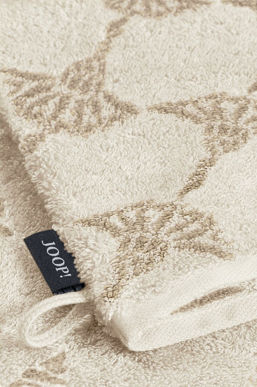 Nahaufnahme eines beigen Waschhandschuhs mit dezentem Muster und einer schwarzen Joop!-Markenlasche.