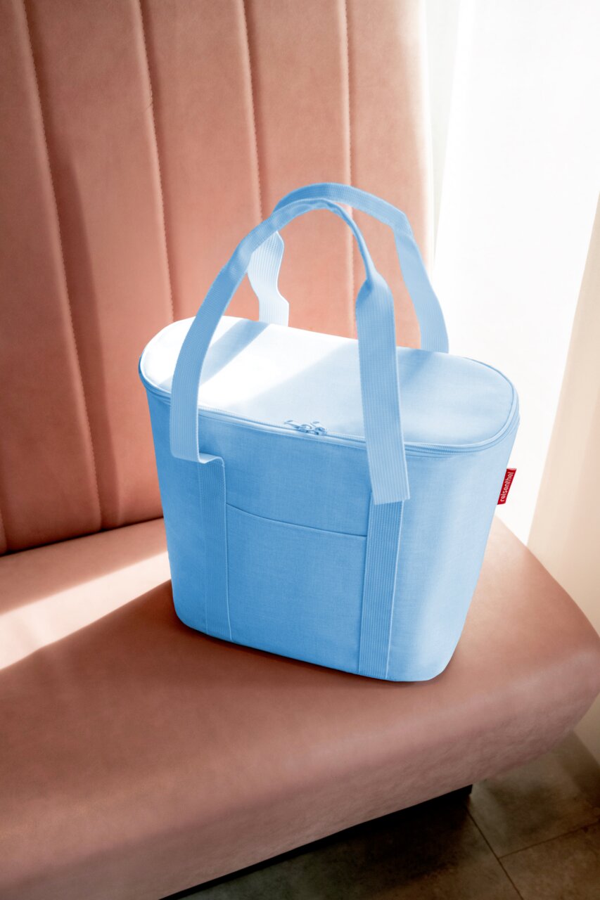 Hellblaue Thermoshopper-Tasche auf einem rosa Sofa, seitliche Perspektive