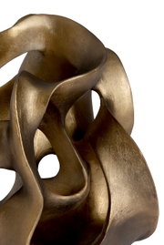 Nahaufnahme eines goldfarbenen, abstrakten Ornaments mit geschwungenen Formen und Öffnungen.