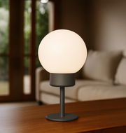 Modernes Akku-Windlicht mit kugelförmigem Leuchtkörper auf einem Tisch, seitliche Perspektive.