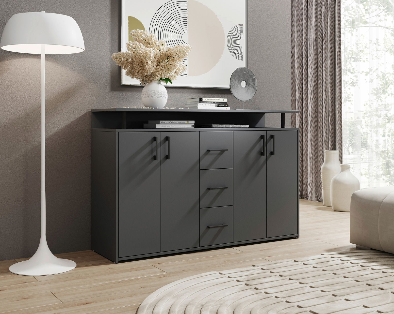 Modernes graues Sideboard mit vier Türen und drei Schubladen, dekoriert mit Büchern und einer Vase, in einem stilvoll eingerichteten Wohnzimmer. Perspektive von vorne.