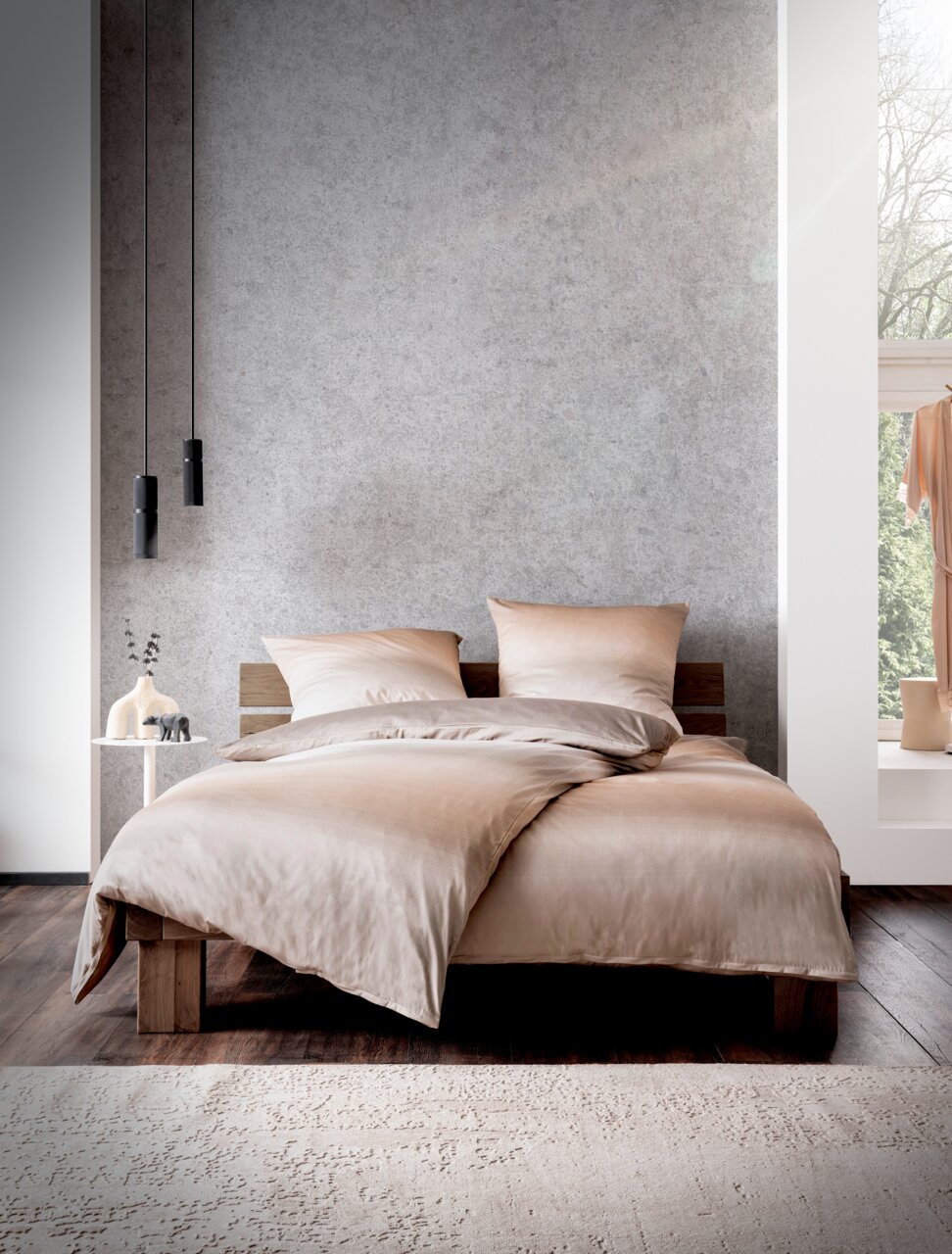 Een set beddengoed in beige op een modern houten bed, gefotografeerd van voren, met een minimalistische decoratie op de achtergrond.