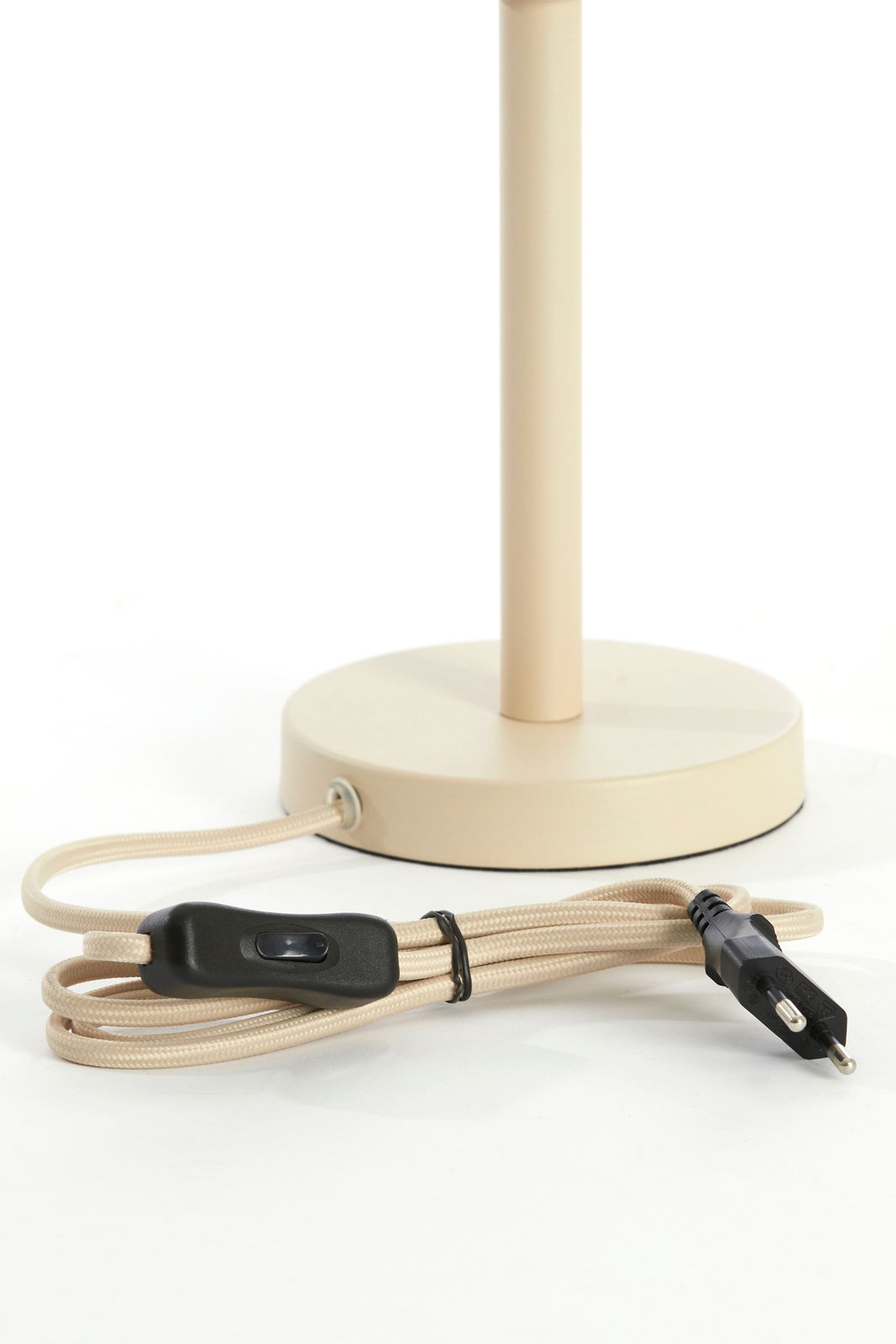 Nahaufnahme eines beigen Lampenfußes mit rundem Sockel und beige ummanteltem Kabel mit schwarzem Schalter und Stecker, seitliche Perspektive.