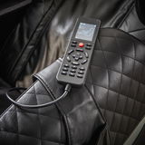 Nahaufnahme eines schwarzen Massagesessels mit einer Fernbedienung auf der Armlehne, die verschiedene Massageoptionen anzeigt.