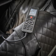 Nahaufnahme eines schwarzen Massagesessels mit einer Fernbedienung auf der Armlehne, die verschiedene Massageoptionen anzeigt.