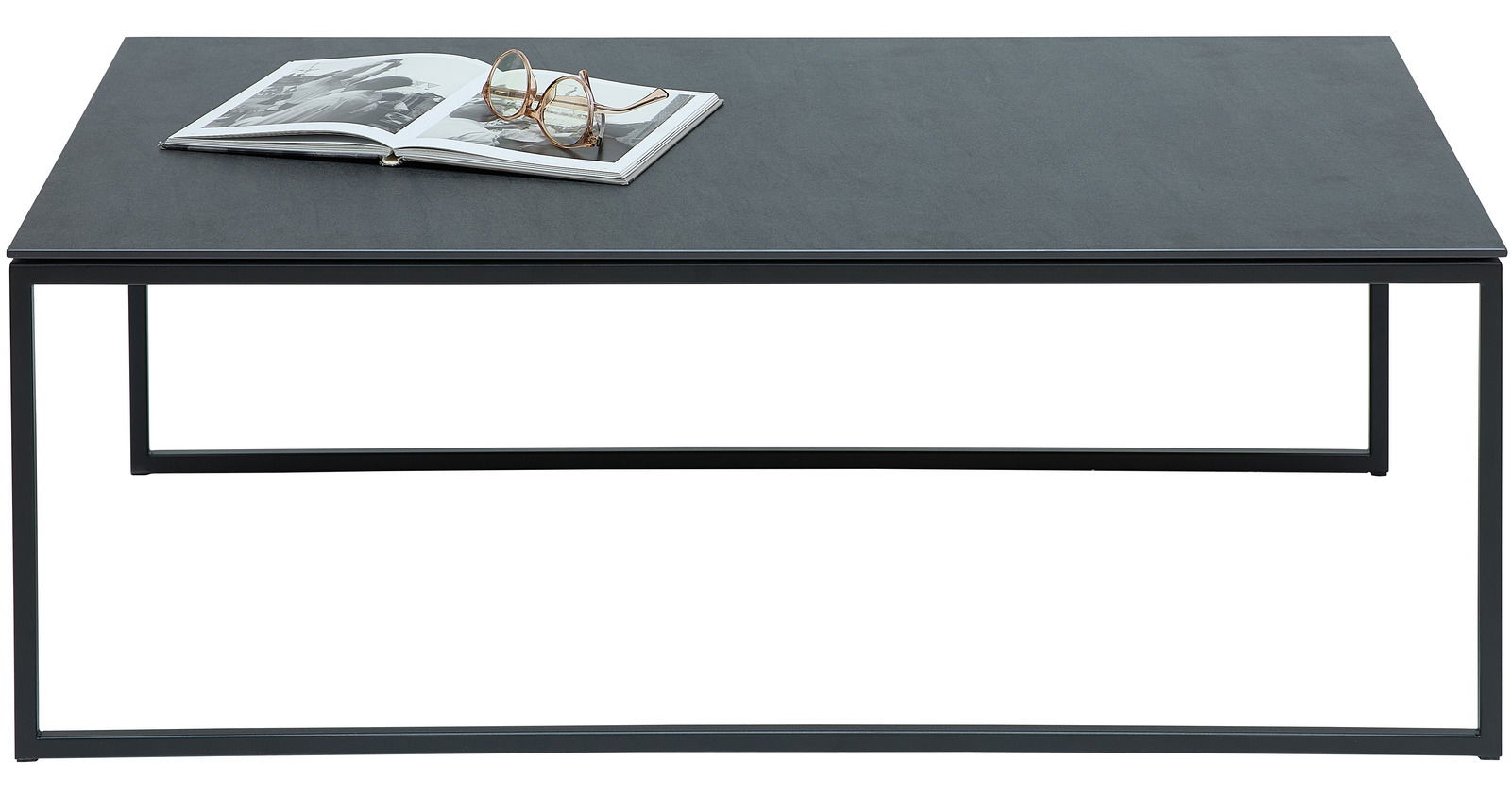 Moderner Couchtisch mit schwarzer Tischplatte und Metallgestell, frontal fotografiert. Auf dem Tisch liegt ein aufgeschlagenes Buch und eine Brille.