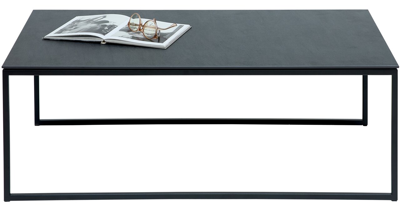 Moderner Couchtisch mit schwarzer Tischplatte und Metallgestell, frontal fotografiert. Auf dem Tisch liegt ein aufgeschlagenes Buch und eine Brille.