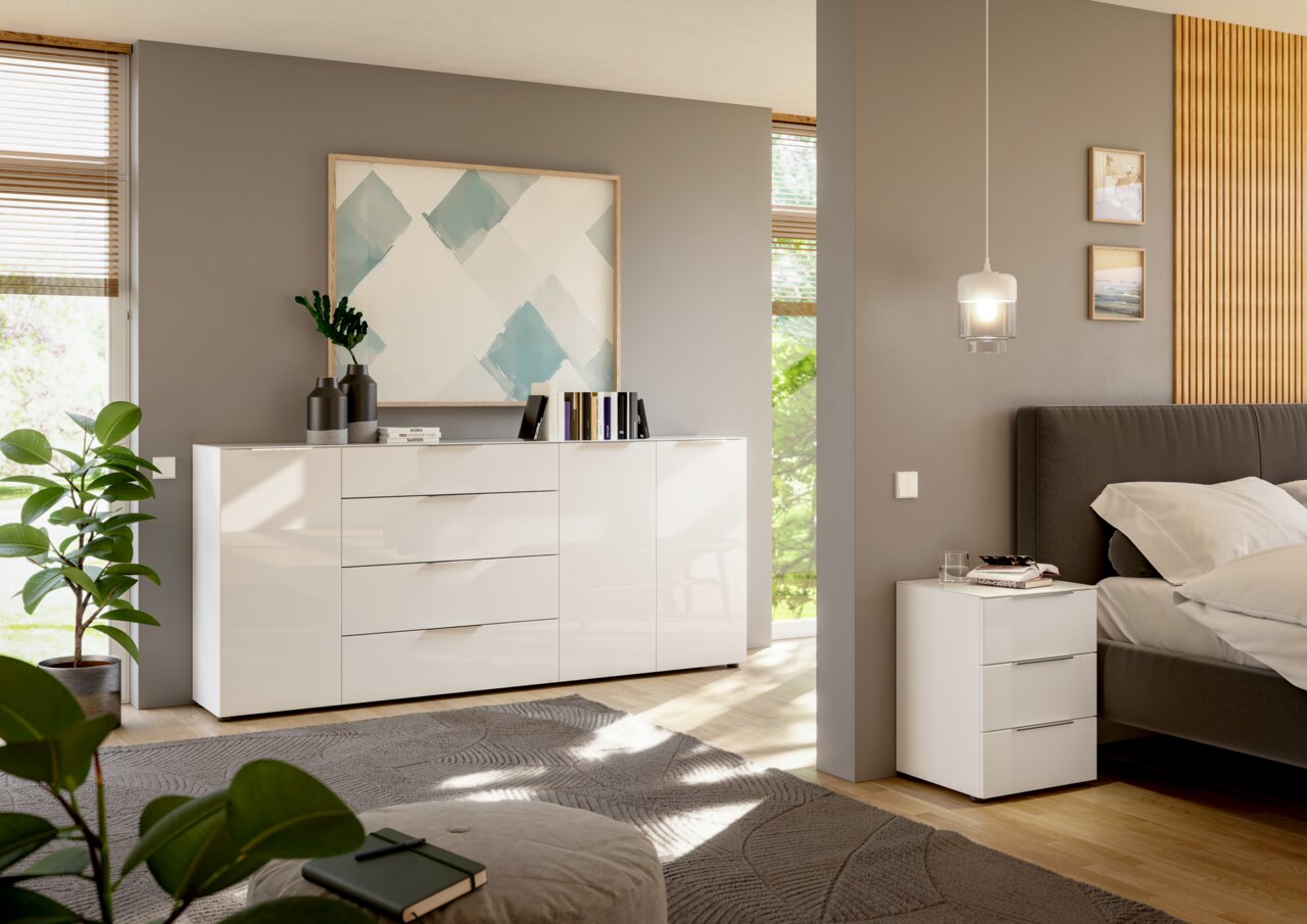 Moderne weiße Kommode und Nachttisch in einem stilvollen Schlafzimmer, seitliche Perspektive