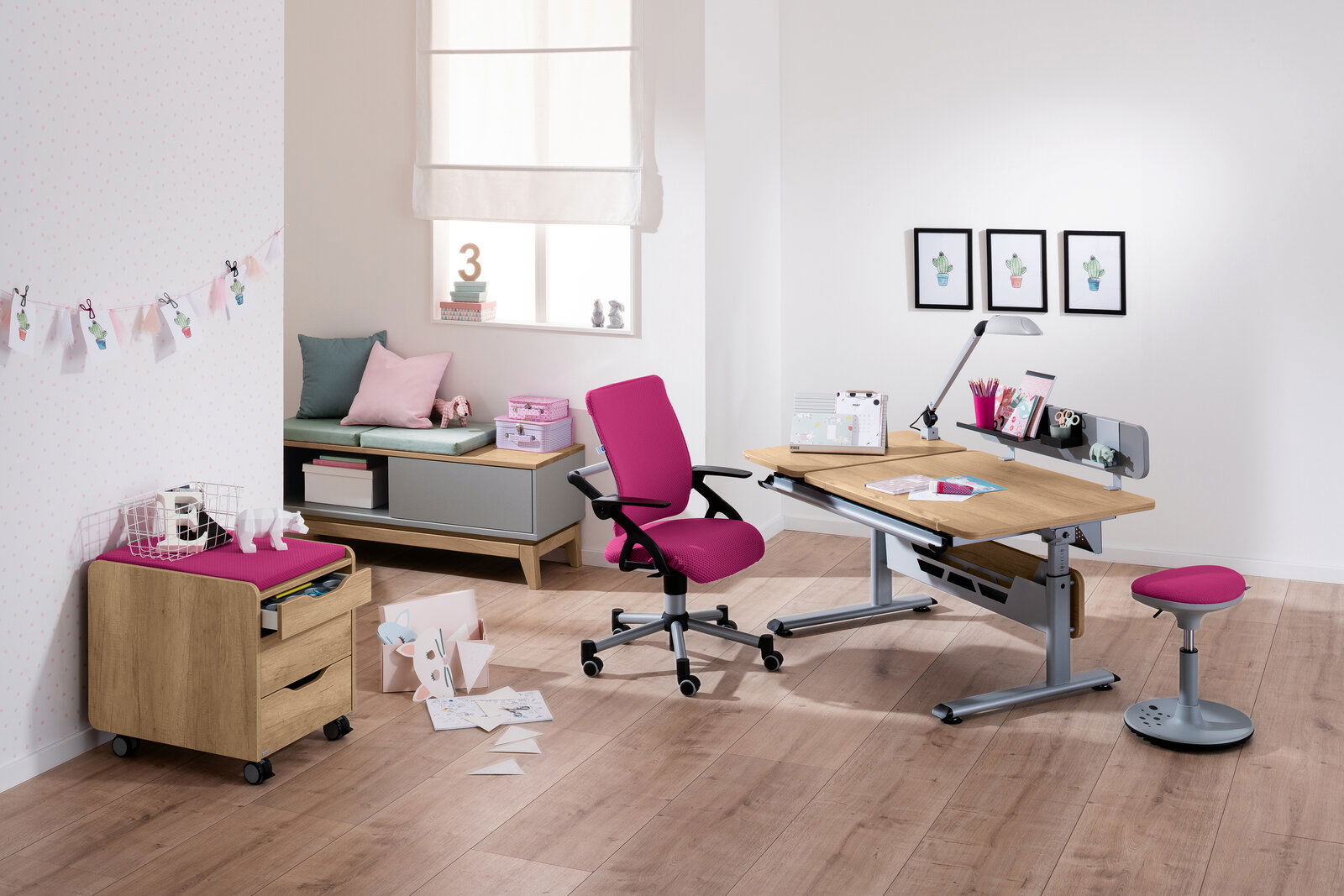 Paidi Schreibtisch DIEGO GT Moderner Schreibtisch mit Holzoberfläche und grauem Metallgestell, umgeben von einem pinken Drehstuhl und Hocker, in einem hellen Raum mit Holzboden, aus der Perspektive von vorne rechts betrachtet.