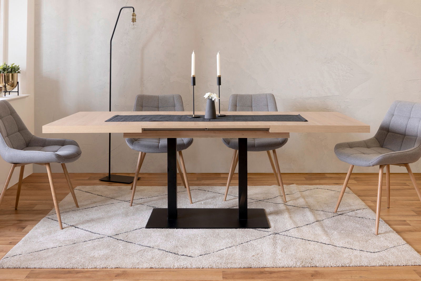 Moderner Esstisch QUADRATO mit hellem Holz und schwarzem Metallgestell, umgeben von grauen Stühlen, aus frontaler Perspektive fotografiert.