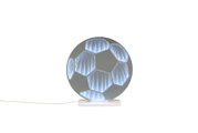 Runde LED-Tischlampe in Fußball-Optik mit blau-weiß leuchtenden Segmenten auf weißem Sockel, Frontansicht vor weißem Hintergrund