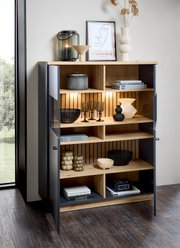 Modernes Highboard mit offenen und geschlossenen Fächern, dekoriert mit Büchern, Vasen und Gläsern, aus einer schrägen Perspektive fotografiert.