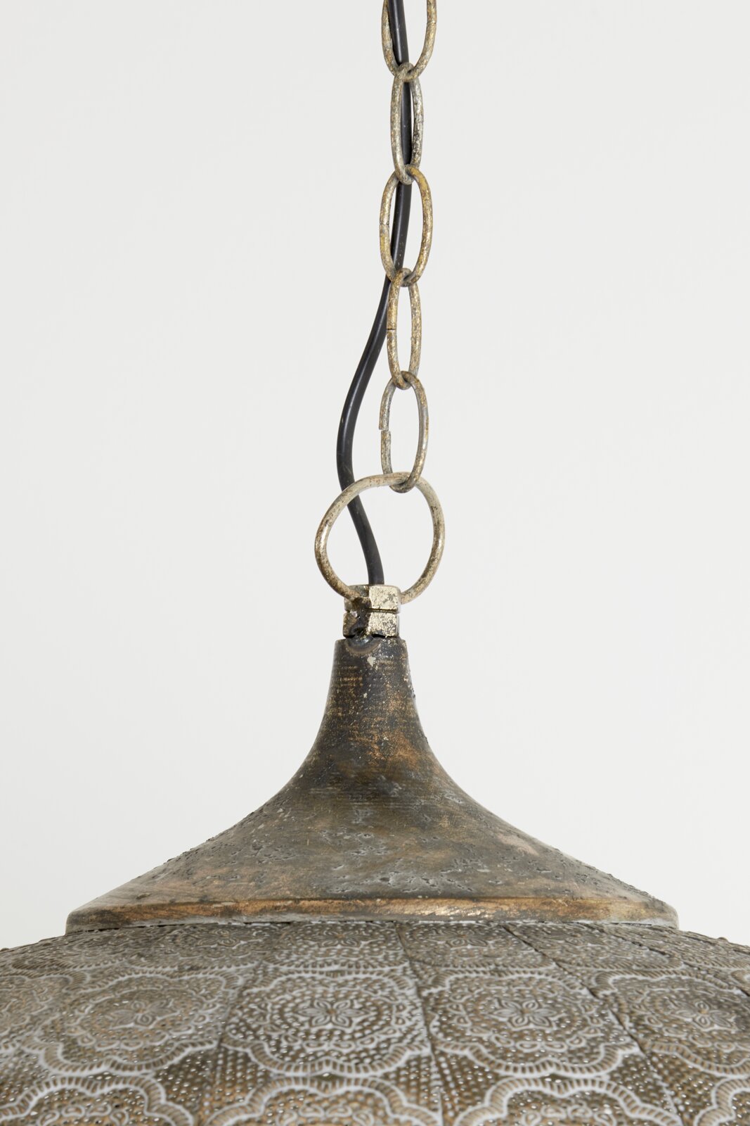 Detailfoto van een hanglamp met antieke afwerking en decoratief patroon, gefotografeerd van onderaf.