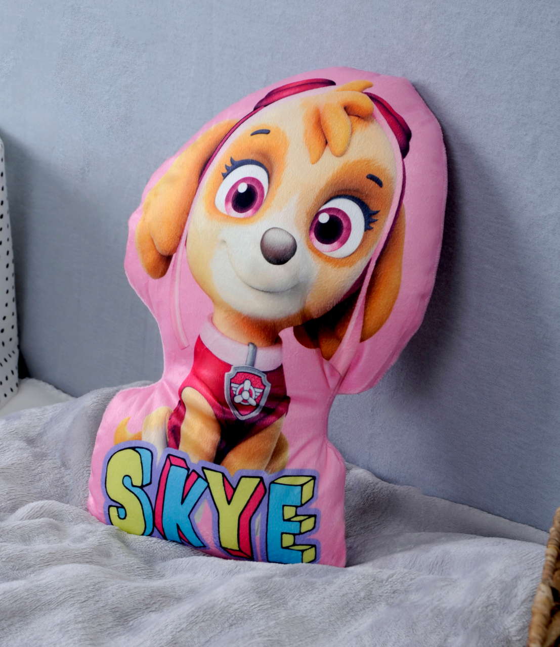 Skye-Formkissen mit buntem Skye-Motiv aus einer Kinderfernsehserie, auf einem Bett platziert, seitliche Perspektive.