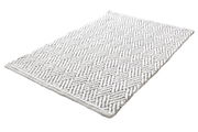 Weißer Badteppich mit geometrischem Muster, perspektivisch von der Seite fotografiert.