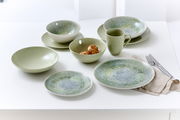 Grünes Geschirrset mit flachen und tiefen Tellern, Schalen und Tasse, von oben fotografiert.