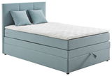 Boxspringbett in hellblauem Stoffbezug mit zwei Kissen, seitliche Perspektive