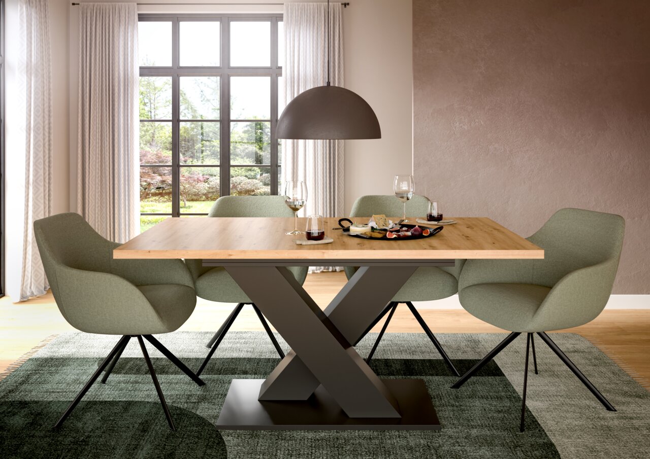 Moderner Esstisch mit X-förmigem Metallgestell und Holzplatte, umgeben von grünen Stühlen, aus der Frontalperspektive.